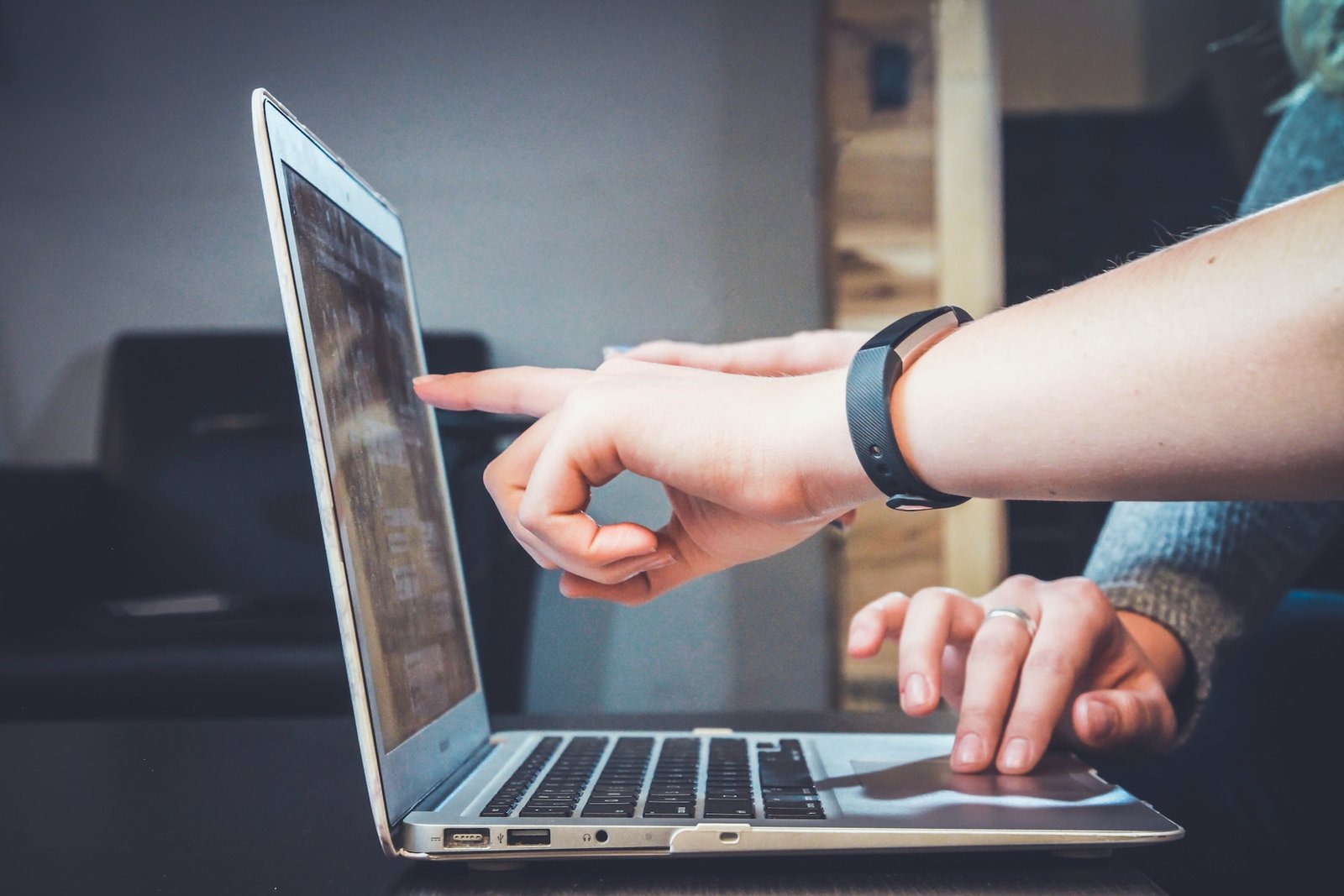 stock image of a person using a laptop and another person assisting them